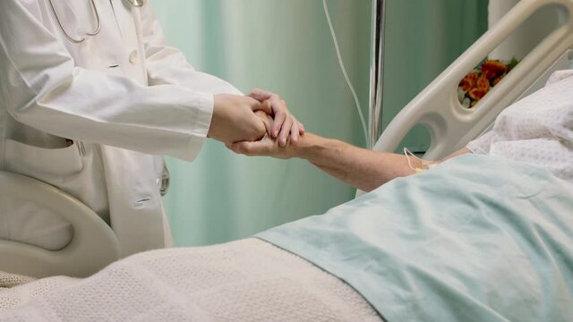 doctor holding hand of old woman in hospital bed comforting elderly patient hospitalized recovering from illness medical professional at bedside giving encouragement health care support