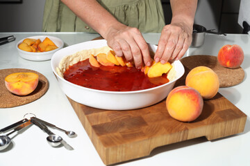Obraz na płótnie Canvas Housewife prepares fresh peach pie. Homemade baking process.