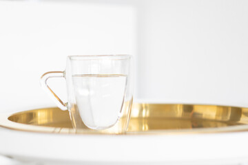 transparent mug with water on a gold tray