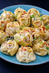 Traditional steamed Kazakh manti garnished with mincemeat and sumah served as close-up on a Nordic design plate