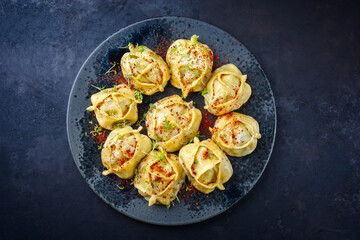 Traditional steamed Kazakh manti garnished with mincemeat and sumah served as top view on a Nordic design plate with copy space