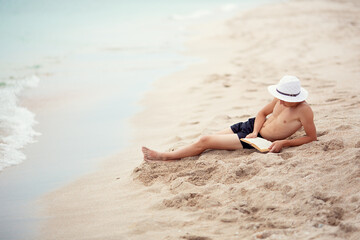 Fototapeta na wymiar A teenager reads a book on the beach