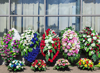 A row of wreaths for burial. The funeral wreaths are made of plastic flowers. Artificial wreaths...