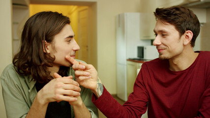 A young man is wiping his friend's mouth during conversation 