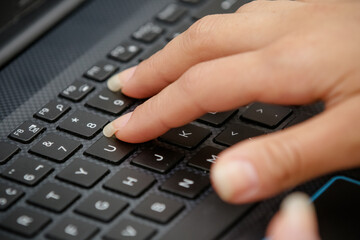 hand on the black keyboard of a computer typing text.
