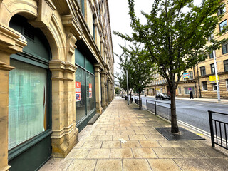 Fototapeta na wymiar View along a tree lined pavement, with adjacent Victorian buildings on, Manor Row, Bradford, Yorkshire, UK