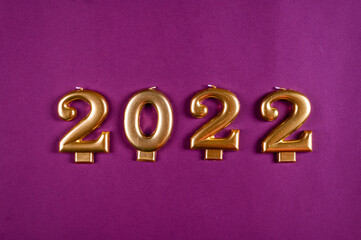 New Year 2022 golden candles on purple background. 2022 year. New year flatly. New year background.