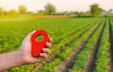 Red location pin on farm field. Buying and selling land. Land market. Plot Boundary Demarcation Service. Legal regulation of property. Agriculture and agribusiness. Landowner's investment. Rent site