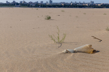 a dirty plastic bottle is lying on a sandy beach