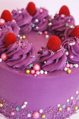purple cake with raspberry decor, meringues and sweet decorations and on a stand