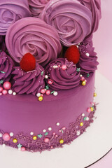 Purple cake with raspberry decor, meringues and sweet decorations and on a stand
