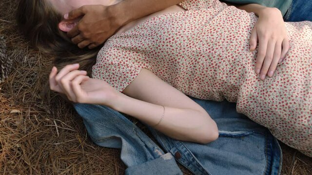 young man touching womans face with hand gently caressing showing affection teenage couple lying on ground in forest woods