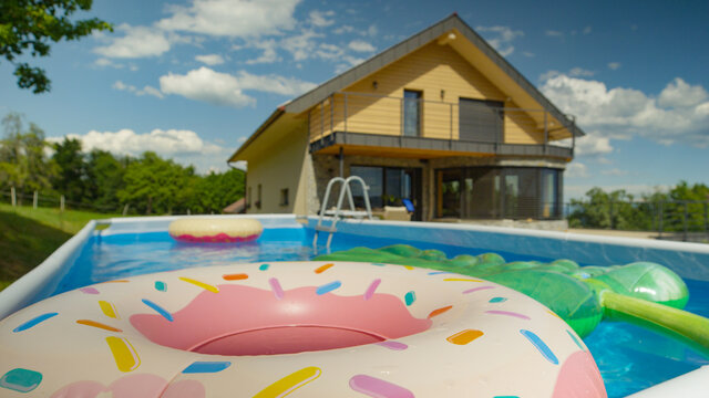CLOSE UP: Colorful Inflatable Toys Float Around Empty Garden Pool In Backyard.