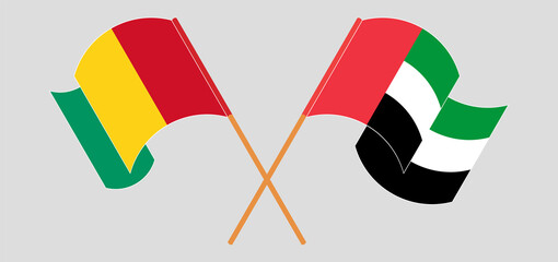Crossed and waving flags of Guinea and the United Arab Emirates