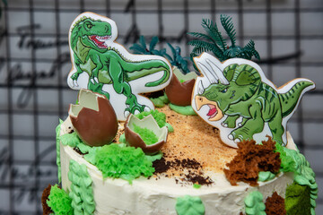 A dinosaur birthday cake. Children's holiday cake decorated with dinosaurs in the Jurassic period jungle.