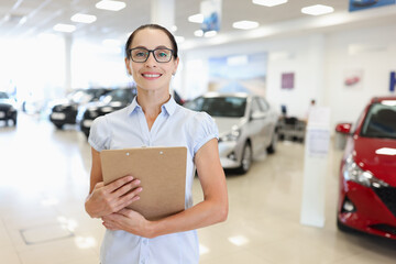 Fototapeta premium Woman manager consultant stands in car showroom closeup