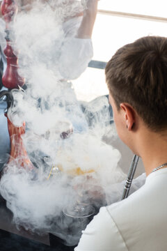 Close-up of man smoking traditional hookah pipe. man exhaling smoke. Hookah and sparks from coals. Shisha, spark, hookah sparks. Young man smokes a fragrant oriental hookah.