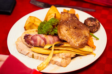 Roast dinner with turkey, pork, pigs in blankets, roast potatoes, parsnips, stuffing, carrots and broccoli 