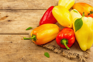 Ripe colorful bell peppers on a wooden background