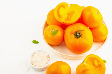 Ripe orange tomatoes with fresh basil. New harvest vegetables on a ceramic stand