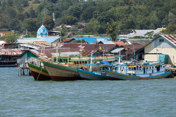 Fototapeta na wymiar Humble houses in Sorong city, and old fishing and freight boats moored in the harbor area, West Papua, Indonesia