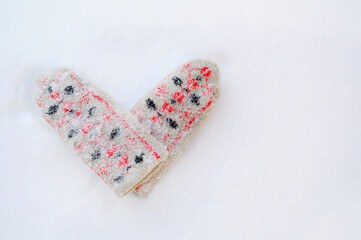 Mittens in the snow. Mittens, sprinkled with snow in the shape of a heart. Valentine's Day. Symbol of love