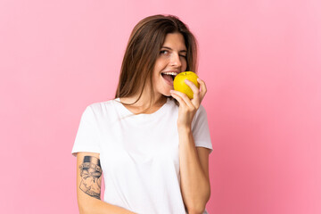 Young slovak woman isolated on pink background eating an apple