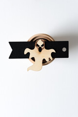 ghost on a black tag on a wooden shape on white