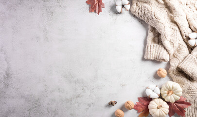 Autumn composition. Pumpkin, cotton flowers, autumn leaves and sweater on stone background. Flat lay, top view with copy space.