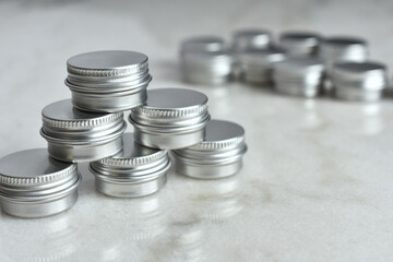 A close up image of several small silver metal sample tins on a white marble table top. 