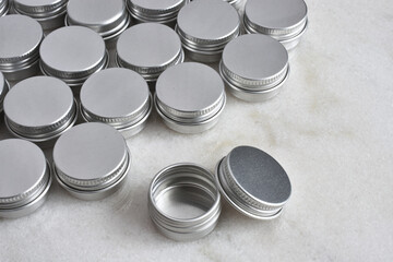 A close up image of several small silver metal sample tins on a white marble table top. 
