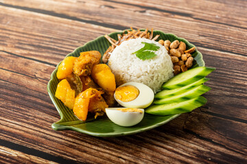 Chicken Curry Nasi Lemak served with coconut rice, cucumber, anchovies, peanuts and eggs 