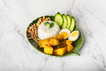 Chicken Curry Nasi Lemak served with coconut rice, cucumber, anchovies, peanuts and eggs 