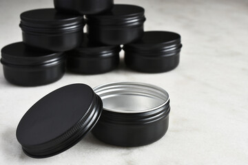 A close up image of large black metal storage tins on a white marble table top. 