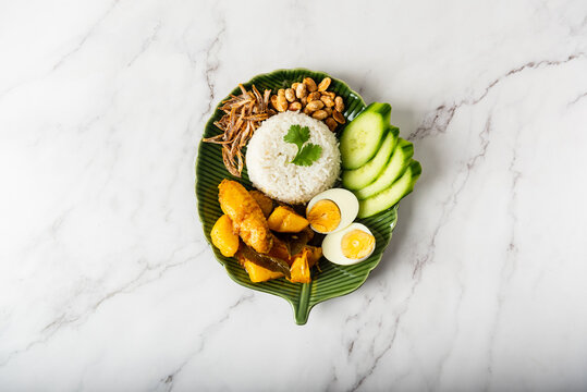 Chicken Curry Nasi Lemak served with coconut rice, cucumber, anchovies, peanuts and eggs 