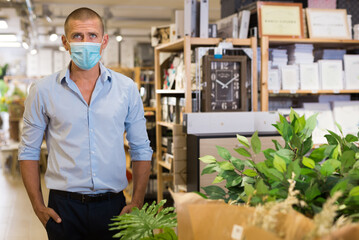 Man in protective mask inspects goods in a hardware store
