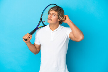blonde tennis player man isolated on blue background having doubts