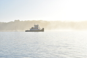 Backlit tugboat in a summer morning fog.  Copy space.  Long Island, New York.