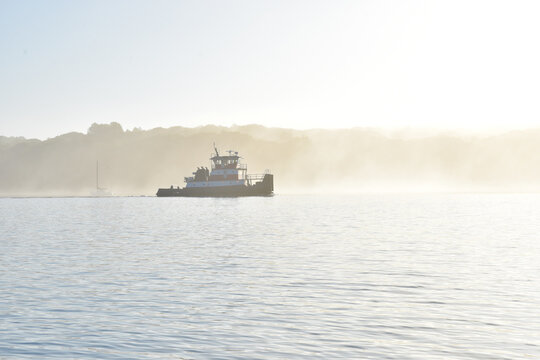 Backlit tugboat in a summer morning fog.  Copy space.  Long Island, New York.