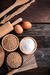 Kitchen utensil for bakery cooking and food ingredients (wheat grain, flour and egg) on wooden...