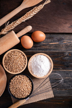 Kitchen utensil for bakery cooking and food ingredients (wheat grain, flour and egg) on wooden background, Table top view