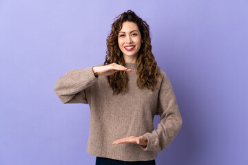 Young caucasian woman isolated on purple background holding copyspace imaginary on the palm to...