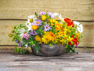 A variegated bouquet of summer wildflowers in a metal cup close-up