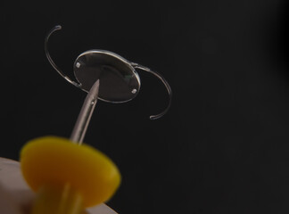 closeup photo of intra ocular lens IOL on the tip of pin