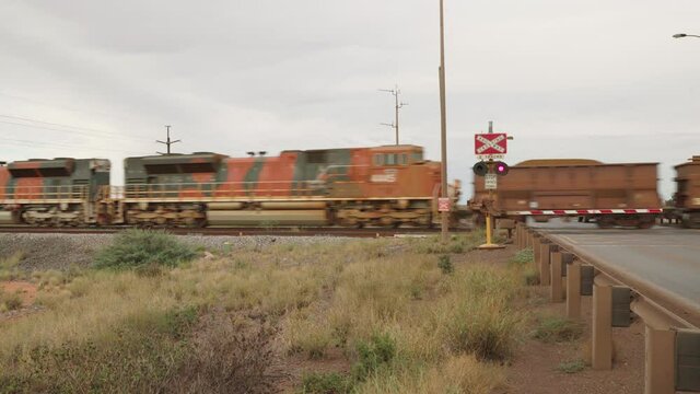 a train carrying iron ore at a level crossing in port hedland of western australia