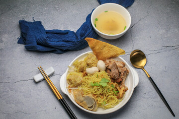 Chinese egg noodle topping slice roasted pork, fish balls, shrimp balls and wontons. Asian food style.