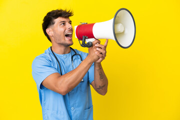 Young surgeon doctor man isolated on yellow background shouting through a megaphone