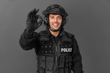 SWAT caucasian man isolated on grey background showing ok sign with fingers