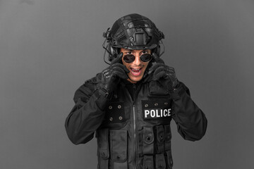SWAT caucasian man isolated on grey background with glasses and surprised