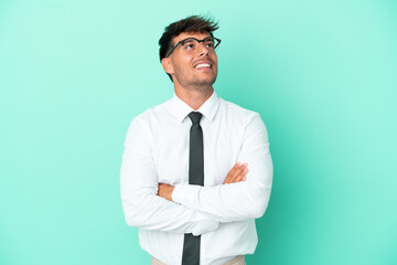 Business caucasian man isolated on blue background looking up while smiling